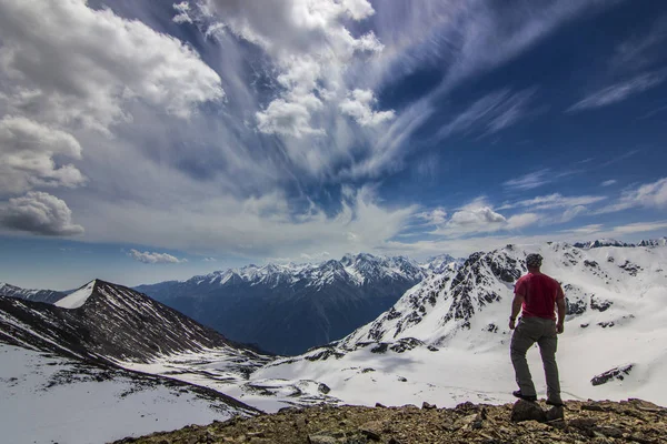 Muž, který stojí na útesu v zasněžených horách — Stock fotografie