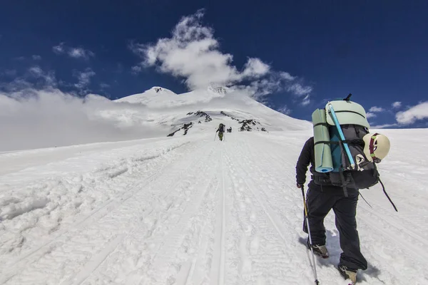 Man with backpack climbing on elbrus in snowy caucasus mountains — Stock Photo, Image