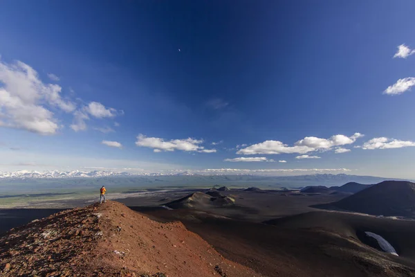 Hombre de pie sobre escoria volcánica con vista a volcanes nevados — Foto de Stock