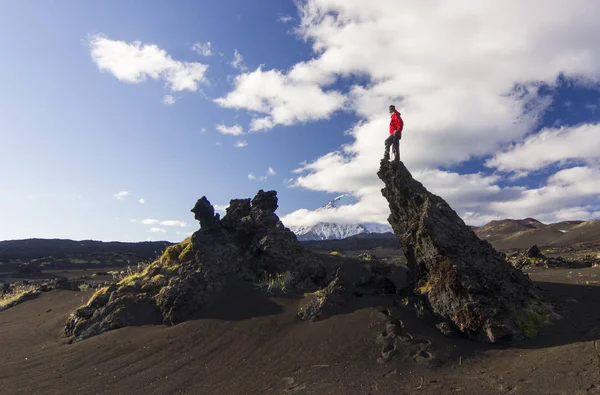 Hombre de pie sobre escoria volcánica con vista al volcán Tolbachik — Foto de Stock