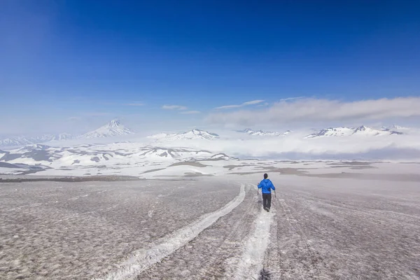 Man on snowy field in kamchatka mountains near covered by snow volcanoes — Stock Photo, Image