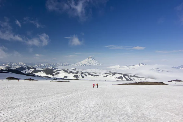 Twee mannen op besneeuwde veld in Kamtsjatka bergen in de buurt van vallende sneeuw vulkanen — Stockfoto