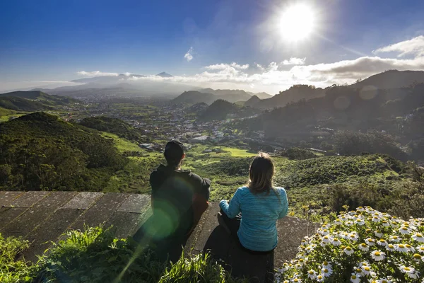 Para siedzi z widokiem na wulkan teide i wiosek o zachodzie słońca — Zdjęcie stockowe