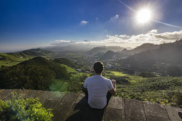 Man sitter med utsikt över byar och teide vulkanen vid solnedgången — Stockfoto