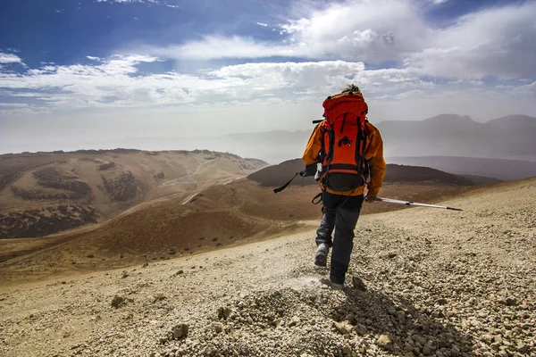 Hombre con mochila roja en camino rocoso en el desierto — Foto de Stock