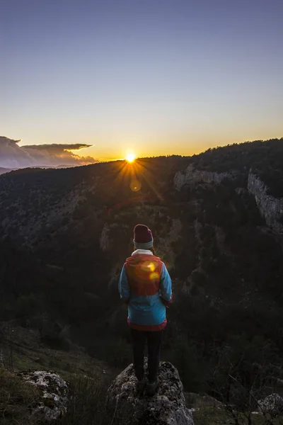 Meisje permanent op een klif in de bergen bij zonsondergang — Stockfoto
