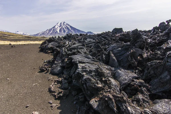 Vista del volcán desde la arena volcánica negra y la lava fría con poca vegetación — Foto de Stock