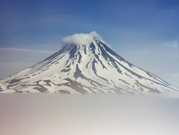 Volcán Vilyuchinsk cubierto de nieve con nubes debajo — Foto de Stock
