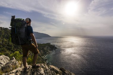 turistik Akdeniz yakınındaki dağlarda bir uçurumun üzerinde duran sırt çantası ile