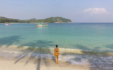 Kız kumlu okyanus sahil üzerinde güneş doğarken phangan Island'da ayakta.