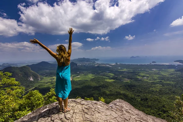 Eller yukarı dağlar aşağıdaki gün batımında kaya üzerinde duran kızla