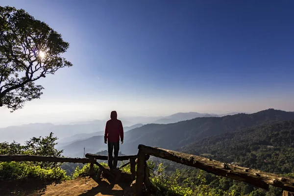 Man standing on rock at sunset with mountains below — Stock Photo, Image