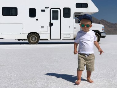 Güzel bir çocuk (bebek) trendy güneş gözlüğü ve beyaz tişört. Bonneville üzerinde (Rv) kamyonet ve karavan