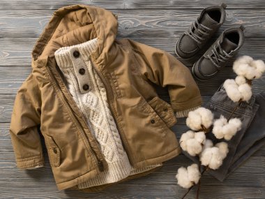 Moda çocuk giyim, Ayakkabı (örgü süveter, kapüşonlu tuval ceket, kot pantolon, süet çizmeler). Küçük çocuk kıyafeti. Kış, sonbahar koleksiyonu. Organik Pamuk. Üstten görünüm, düz yatıyordu