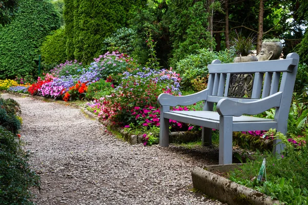 Romantic park alley with flowers and wooden bench