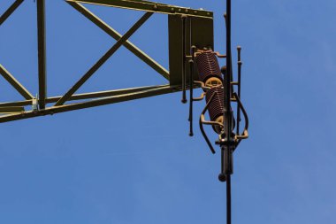 Mavi gökyüzünün arka planına karşı yüksek voltajlı sütunlardaki izolatörler