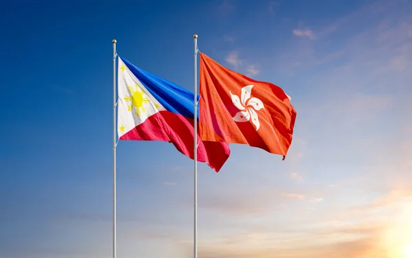 The Philippine and Hong Kong flags fly together in the wind against the sunrise sky. The concept of cooperation and competition in economics and politics. Flag of the Philippines to the left of Hong Kong.
