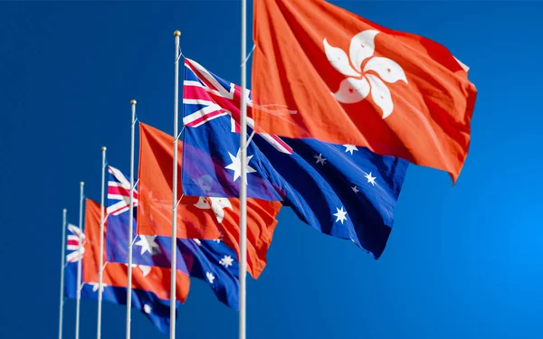 The Aussie and Hong Kong flags fly together in the wind against the cloudy blue sky. The concept of cooperation and competition in economics and politics. Flag of the Australia to the left of Hong Kong.