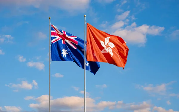 The Aussie and Hong Kong flags fly together in the wind against the blue sky. The concept of cooperation and competition in economics and politics. Flag of the Australia to the left of Hong Kong.