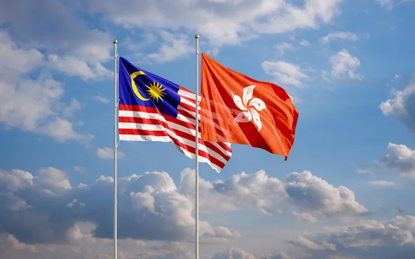 The Malaysian and Hong Kong flags fly together in the wind against the cloudy blue sky. The concept of cooperation and competition in economics and politics. Flag of the Malaysia to the left of Hong Kong.