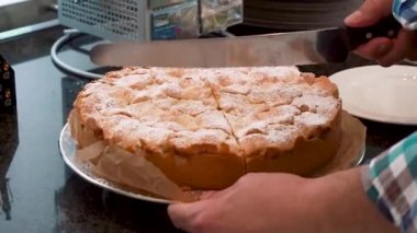 Keskin mutfak bıçağıyla taze pişmiş altın kabuklu elma pasta dilimleme adam