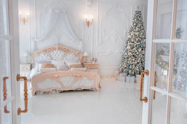Bright White Bedroom Iterior with Christmas New Year Tree decor and lights seen through the open glass doors