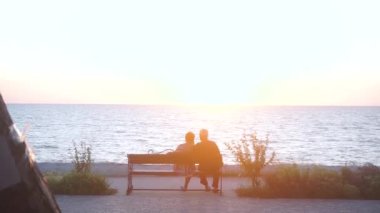 Deniz kenarında bir bankta oturan yaşlı çift ya da tatilde okyanus. 