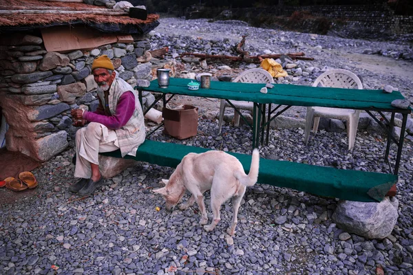 Almora, Uttarakhand / Hindistan - Aralık 2019: Sabah çayını köpeğiyle içen bir adam.