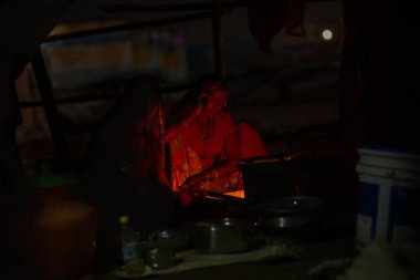 Puşkar, Rajasthan / Hindistan - Kasım 2019: Çingene bir kadın aynı anda arıyor ve pişiriyor.