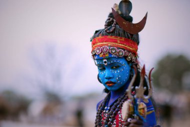 Puşkar, Rajasthan / Hindistan - Kasım 2019: Lord Shiva kılığına girip her yıl düzenlenen Pushkar fuarında turist ağırlamak isteyen bir çocuk.