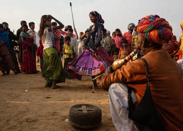 Puşkar, Rajasthan / Hindistan - Kasım 2019: Pushkar kentinde düzenlenen yıllık çoklu hayvan fuarı ve kültür festivalinde sokak seyircisi için dans eden genç bir kadın.