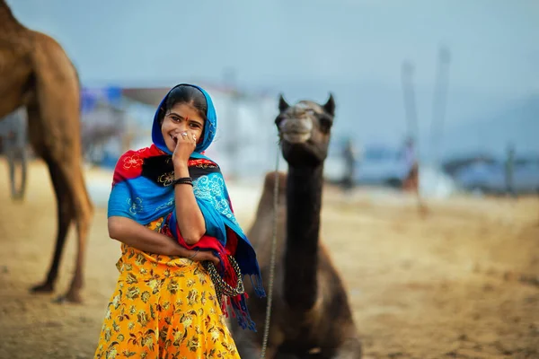 Puşkar, Rajasthan / Hindistan - Kasım 2019: Pushkar kentinde düzenlenen yıllık çoklu hayvan fuarı ve kültür festivalinde bir deve sahibi kadın kameraya poz verdi.