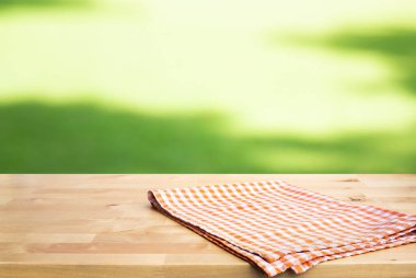 Kontrol edildi, ahşap masa örtüsü arka planda bulanık yeşil avluda. Piknik konseptleri. Anahtar görsel gıda ve içecek ürünleri için dizayn.