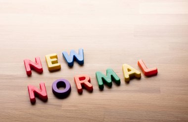 Ahşap masa üzerinde renkli metin mesajı olan yeni normal kavramlar. Yaşam tarzı ve rutini değişiyor