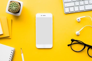Akıllı telefon ve modern aksesuarlarla dolu ofis masasının üst görüntüsü, arka plandaki malzemeler. Düz dizayn. İş kavramları.