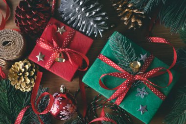 Süslü hediye kutusu ve ahşap masa arkasındaki süs eşyası içeren mutlu noel kavramları. Kış mevsiminin tebrik etkinliği fikirleri.