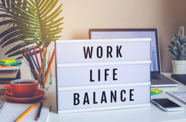 Çalışma Hayatı Dengesi kavramları, ofis masasının üstündeki ışık kutusuna yazılmış metinlerle. Başarılı olmak için olumlu duygu. Vücut sağlığı
