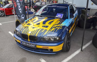 Özel BMW E46 sedan, kaputunda belirgin Ukrayna Tryzub (arması) bulunan koyu mavi ve sarı bir üniforma
