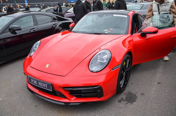 Modern kırmızı Porsche 911, zamansız bir spor araba ikonu. Pürüzsüz, gösterişsiz bir coupe, kendine has yuvarlak farları ve pürüzsüz, gösterişsiz bir ön fasyası var.