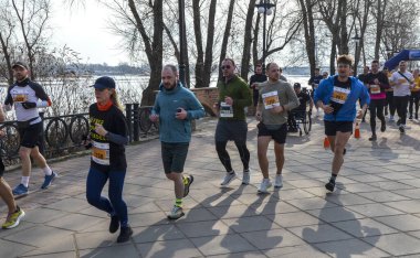 Değişik koşuculardan oluşan dinamik bir grup manzaralı ağaçlar ve deniz manzaralı yollar arasında etkin bir maraton etkinliğine katılıyor.