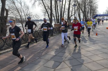 Değişik koşuculardan oluşan dinamik bir grup manzaralı ağaçlar ve deniz manzaralı yollar arasında etkin bir maraton etkinliğine katılıyor.