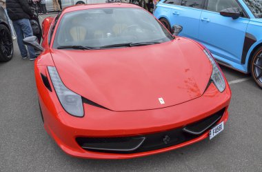 Klasik kırmızı Ferrari 458 Italia, orta motorlu spor araba parlak, aerodinamik tasarım, belirgin Ferrari logosu ve siyah alaşımlı tekerlekleri olan agresif ön fasya.