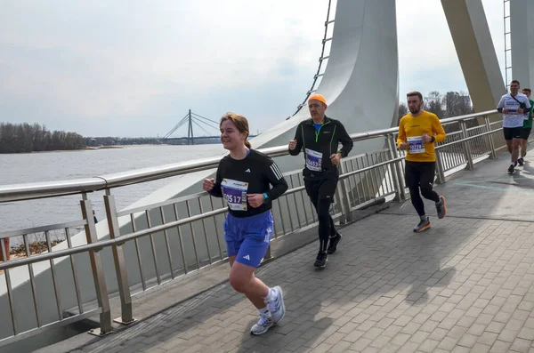 Şehir köprüsünde organize bir maratonda koşan sporcular, adanmışlık, zindelik ve rekabet sergiliyorlar.