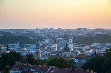 Güzel Lviv günbatımı, şehrin tarihi mimarisini gözler önüne seriyor. Katedraller ve çan kuleleri de dahil. Bulanık gökyüzüne karşı.