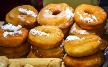 Taze kızartılmış, toz şekerle tozlanmış altın esmer çörekler, hamur işi gibi metal bir tepsinin yanında duruyor.