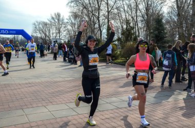 Koşucular manzaralı bir park alanı üzerinden yarışma maratonuna katılıyorlar. Çeşitli katılımcılar ellerinden gelenin en iyisini yaparak spor ve toplum ruhunu kucaklıyorlar.