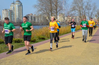 Maraton etkinliği sırasında şehir yolunda koşan sporcular doğa ve su kaplaması enerjisi ve açık hava ortamında kararlılıkla kent zeminine karşı mücadele ediyorlar.