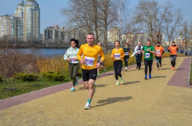 Maraton etkinliği sırasında şehir yolunda koşan sporcular doğa ve su kaplaması enerjisi ve açık hava ortamında kararlılıkla kent zeminine karşı mücadele ediyorlar.