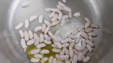 Beyaz fasulye, sucuklu fasulye güveci yapmak için düdüklü tencerede yavaş bir hızda düşüyor..