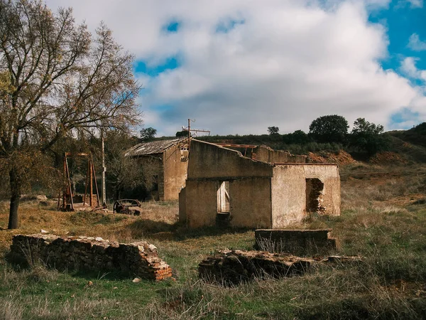 Abandoned house in ruins in the Andalusian countryside, surrounded by bushes and green area